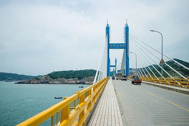 在茫茫的碧蓝大海上飞跃过一条蓝色"长龙",黄色的三礁江大桥五个大字