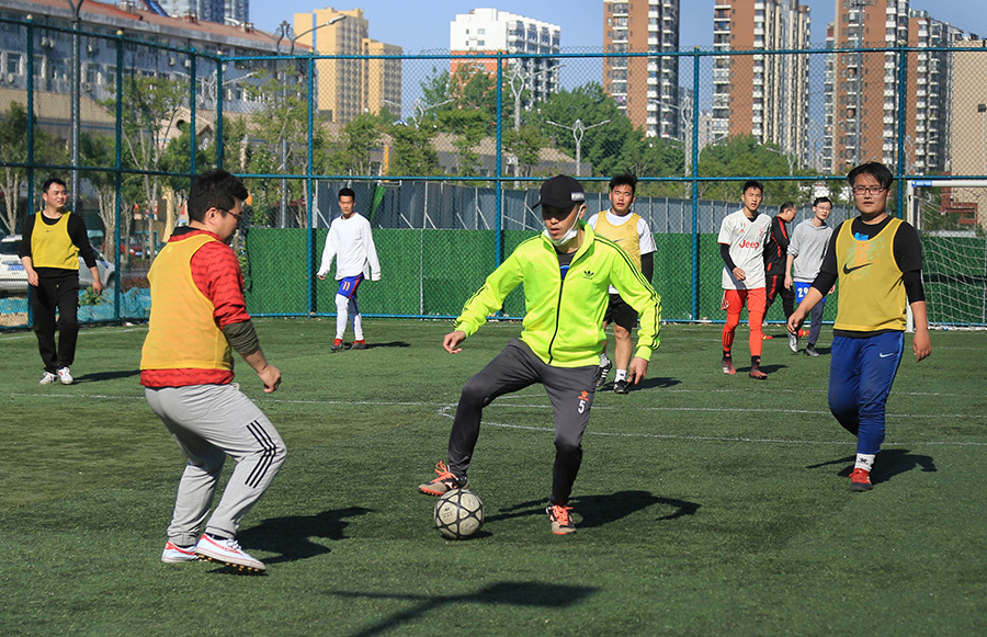25日,小伙子们在城区东俊体育场踢足球.