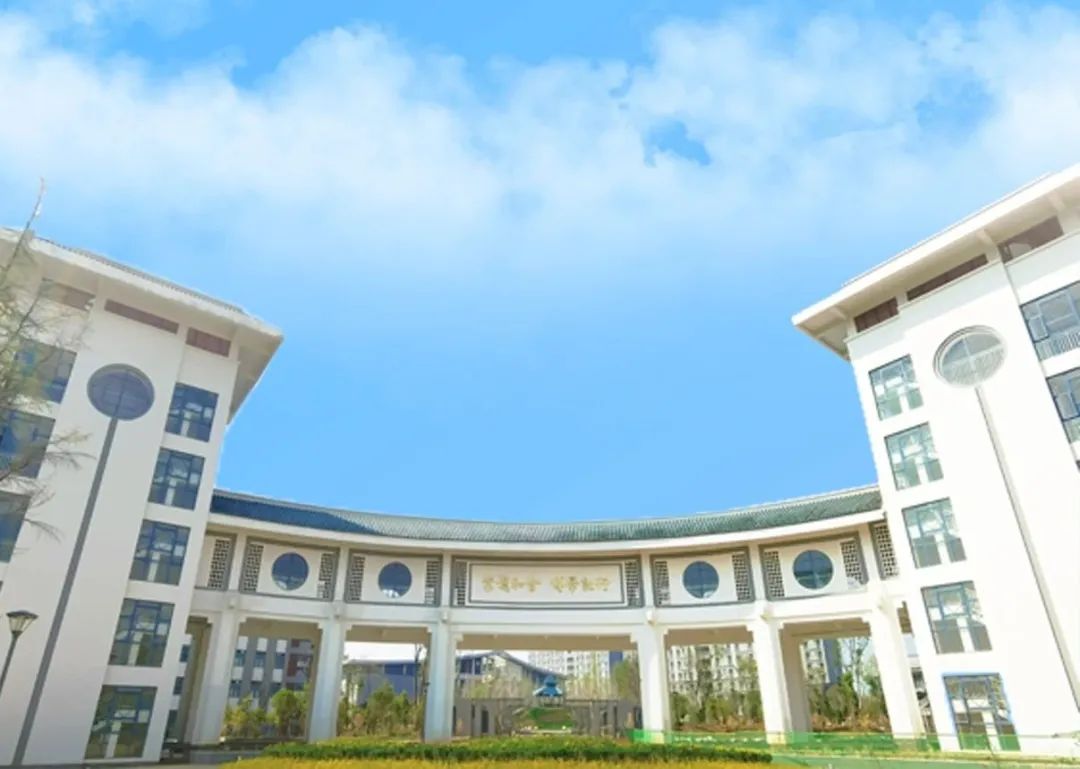 在云南中医药大学北门返校入口处,一块写有"孟夏云中美,熟地盼君归"的