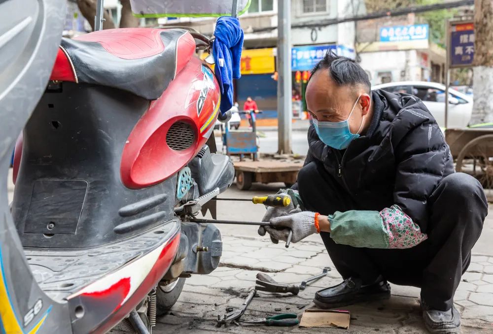 四川南充市延安路一修摩托車店烣復營業,師傅正幫顧客修車