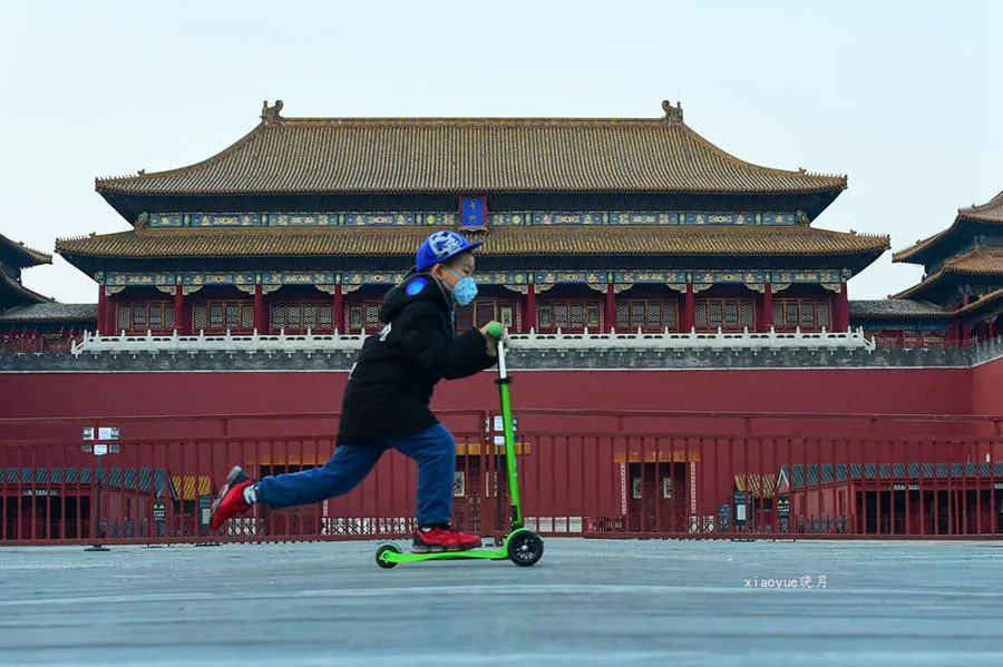 2月25日在故宫午门前,一位小朋友推滑滑板车经过午门