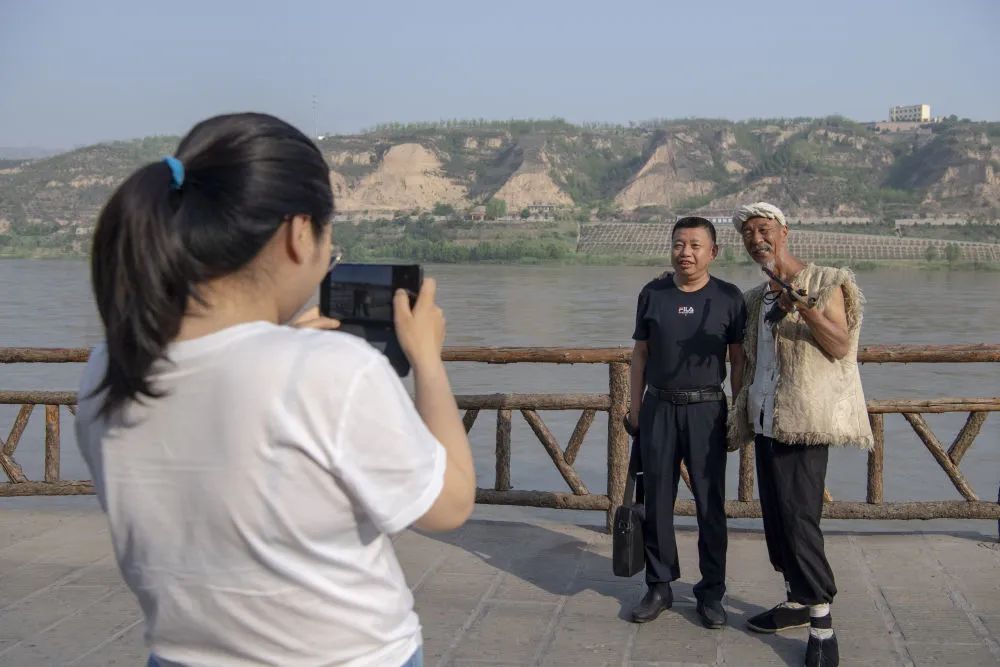 6月10日,李世喜(右)和游客在古镇里合影.