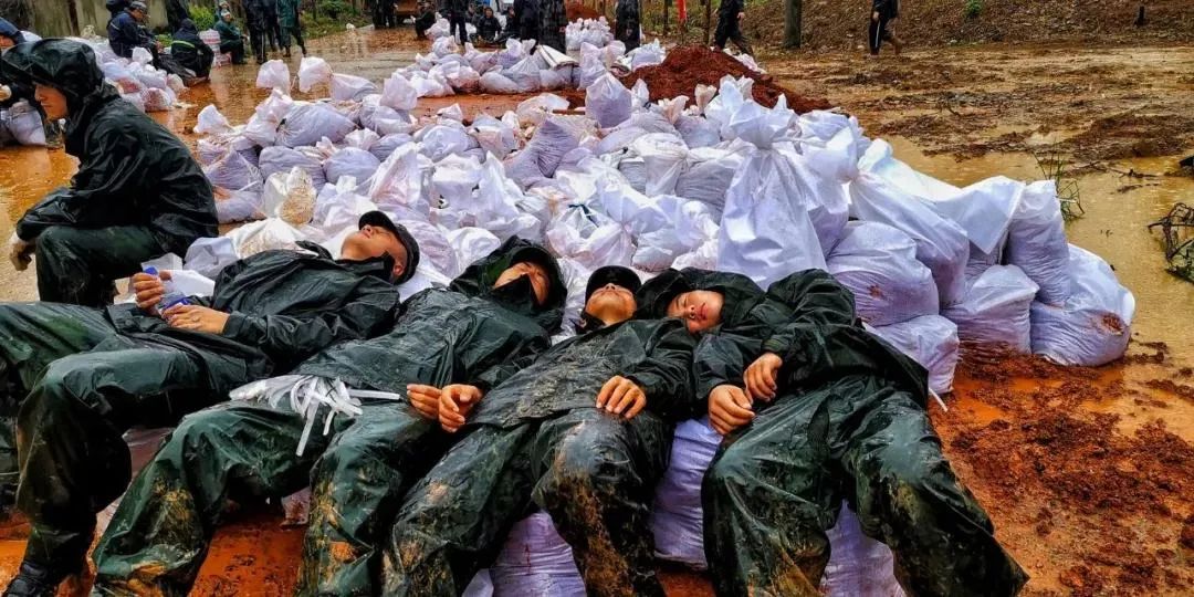 战士们他们是来自武警上海总队在雨中挥铲洒汗装填防洪沙袋身着雨衣的