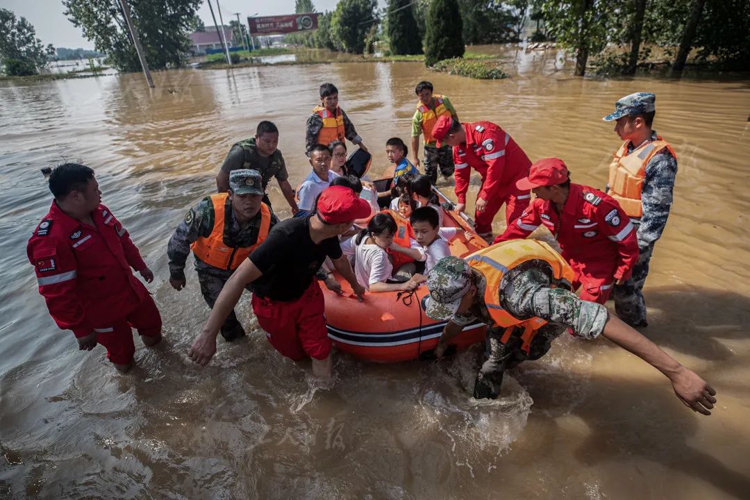 7月20日,救援人员驾驶皮艇和冲锋舟将受困群众转移出去