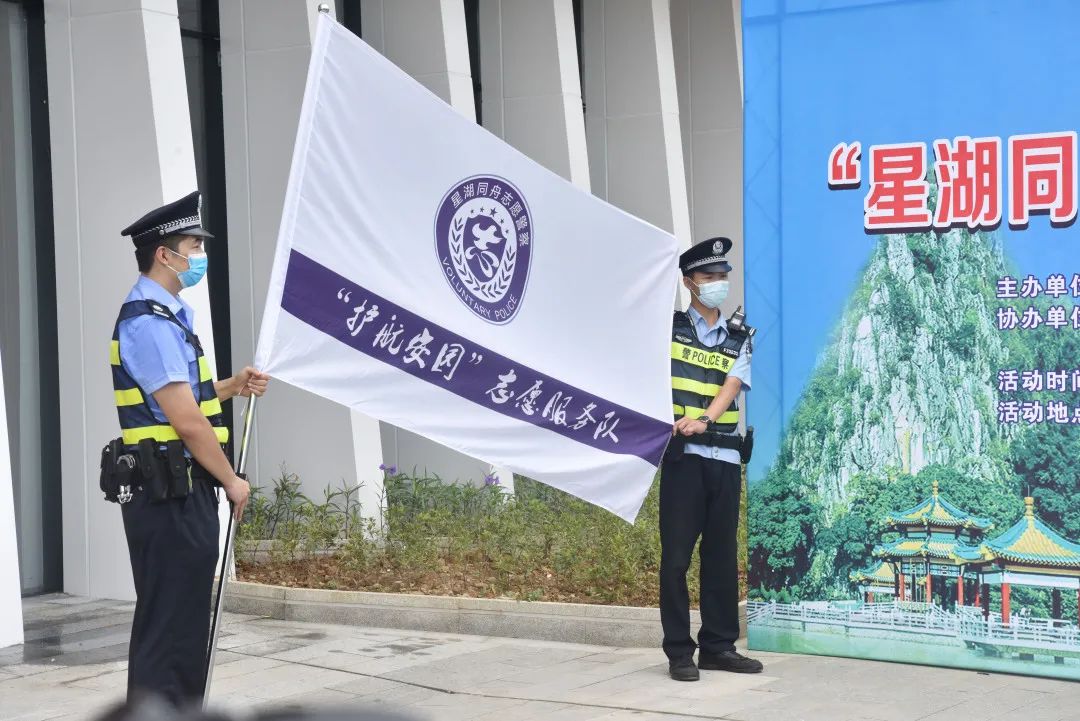华为志愿警察授旗,队长庄重接过队旗迎风挥舞,白底蓝标的旗帜迎风飘扬