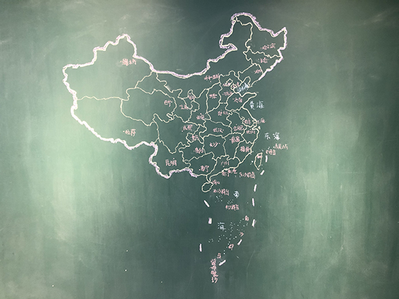 王亚楠一家三口在家里黑板上手绘的中国地图.