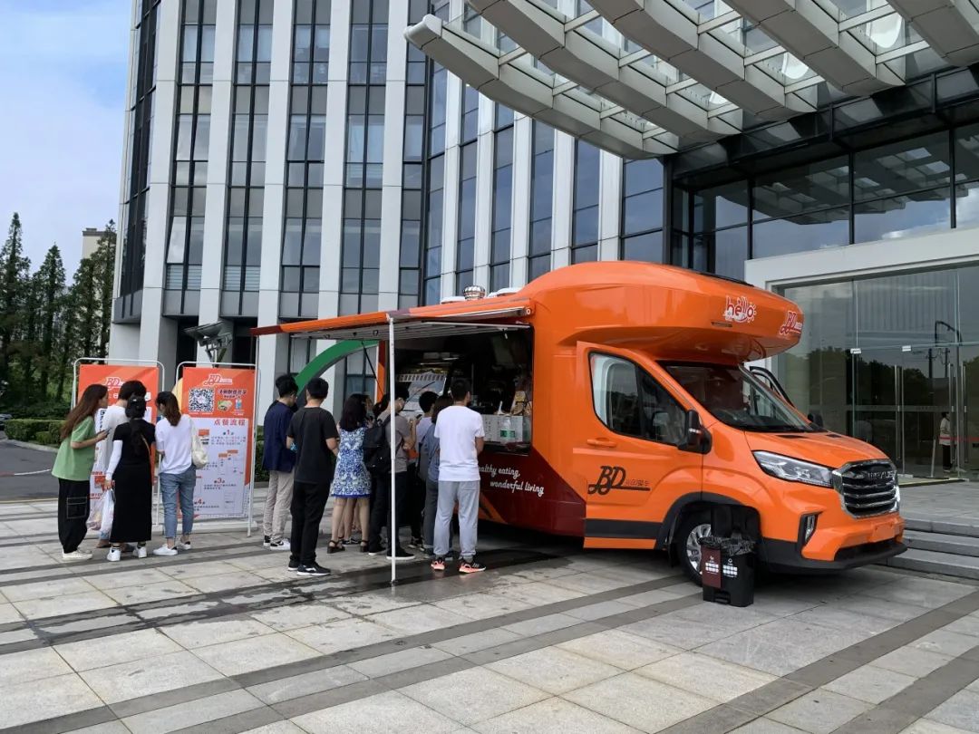 就能看到一辆鲜亮的橘色流动餐车停靠在大楼下,餐车旁早已排起了长长