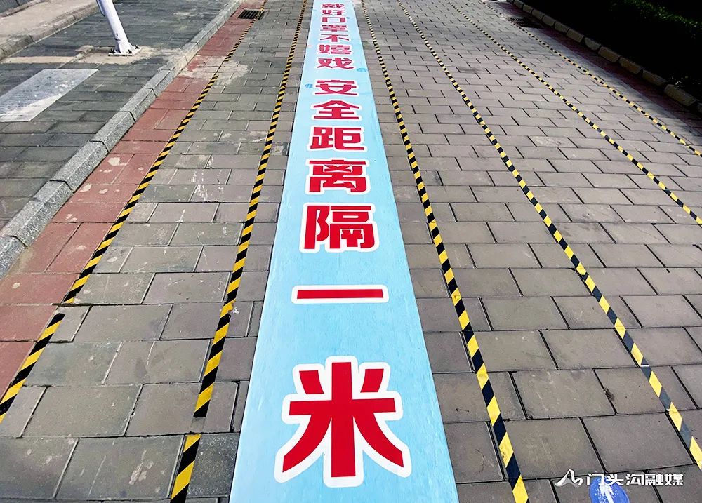 分校的校门口看到,地面已施划了四条通道,并张贴了测温点,一米线标识