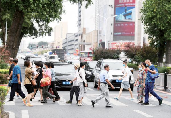 街交會處的無信號燈路口,經過的車輛主動停在斑馬線前禮讓行人通過