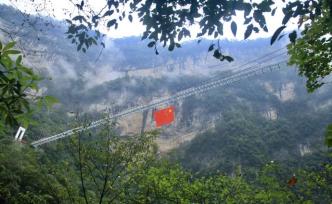 湖北三峡竹海330米高空玻璃桥上悬挂巨幅国旗，鲜艳夺目
